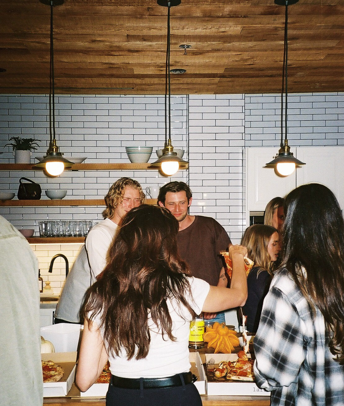 Guests gathered round the kitchen island under pendant lights
