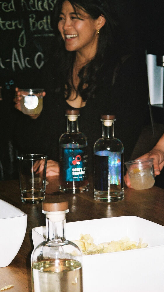 A laughing guest holding a drink behind a row of Sprizzini bottles