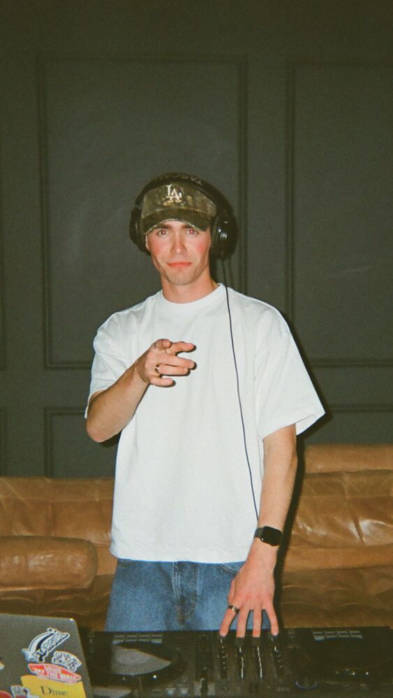 The DJ pointing at the camera from behind the decks