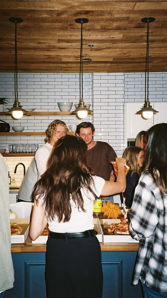 Guests gathered round the kitchen island under pendant lights