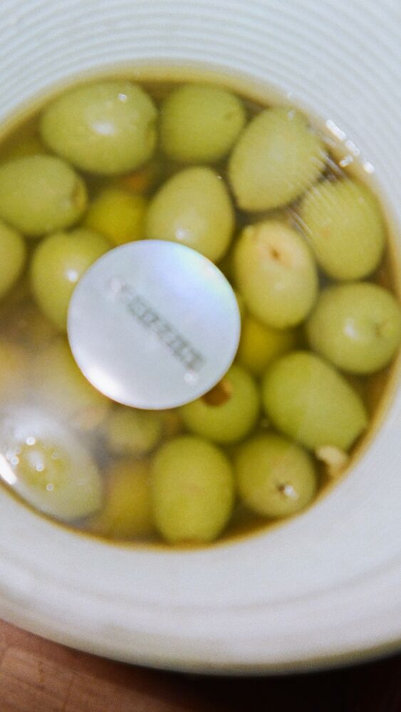 A big tin of green olives seen from above