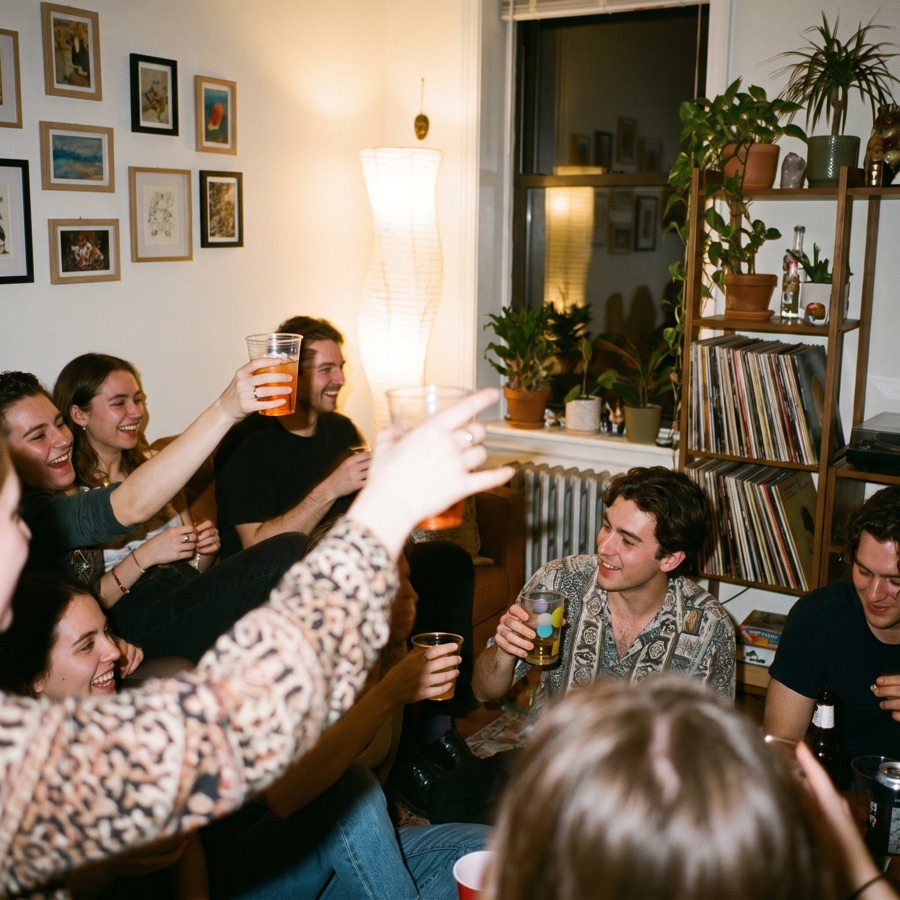 A house party mid-toast, arms up in the lamp light